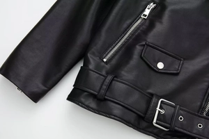Detailed close-up of a black faux leather moto jacket with silver hardware and zippers