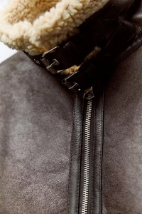 Detail of dark brown leather jacket collar with thick beige shearling lining and metal buckles