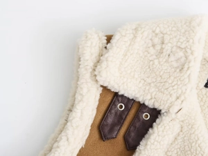 Détail d'un gilet Y2K en daim marron avec doublure en peau lainée et lanières en cuir à boucle