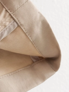 Detailed close-up of the khaki trench coat stitching and twill fabric texture