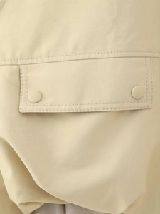 Detailed macro view of beige cargo vest pocket featuring matte snap button closures
