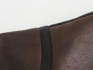 Close-up of vintage brown faux leather texture with black piping on biker jacket