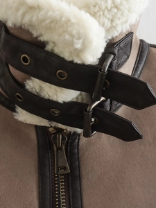 Detail of vintage brown suede jacket featuring white shearling collar and leather buckles