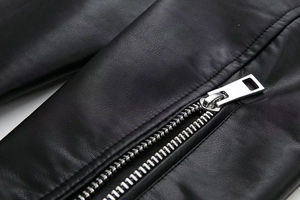 Detail view of the silver metal zipper and smooth black faux leather texture on the Y2K jacket