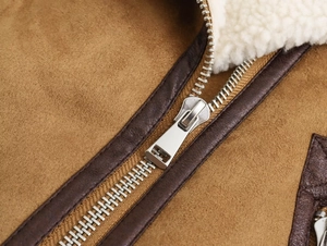 Détail d'une fermeture éclair argentée sur une veste en daim marron avec doublure sherpa