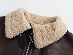 Details einer dunkelbraunen Lederjacke mit beigem Lammfellkragen und silbernem Reißverschluss