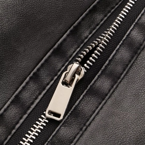 Détail macro du zip en métal argenté et texture grainée sur veste en cuir PU noir