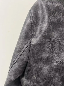 Detail of vintage black faux leather jacket showing distressed texture and double stitching