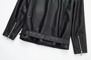 Detail of black faux leather biker jacket with silver zippers and belted hem finish