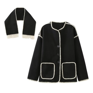 Close-up of black wool coat with white scalloped lace edges and matching fringe scarf