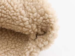 Macro shot of warm beige sherpa fleece lining on the Y2K cropped jacket