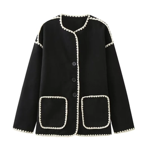 Detail shot of black tweed jacket featuring cream crochet lace trim and textured buttons