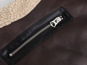 Nahaufnahme der braunen Kunstlederjacke mit Silber-Reißverschluss und beigem Fleece-Futter