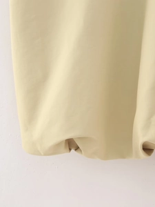 Detail of the pleated hem and smooth beige fabric on the Y2K style zip-up vest jacket