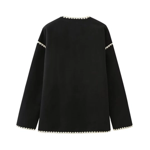 Detail of black long-sleeve top featuring intricate cream lace crochet trim on the back