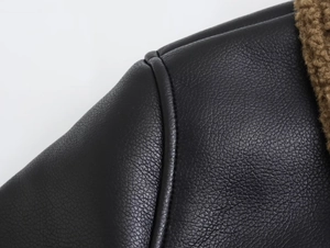 Détail macro d'une veste en cuir noir avec bordure en peau lainée marron et coutures