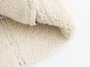 Gros plan sur la texture en polaire sherpa blanche et le matériau épais du gilet