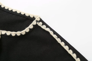 Close-up of contrast crochet trim detail on black wool coat neckline and thick fabric