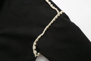 Detailed macro view of black wool coat featuring elegant white crochet lace trim edges