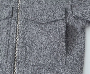 Detail view of the thick gray boucle texture and zipper closure on this short jacket