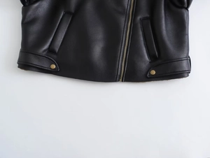 Détail d'un blouson motard noir en similicuir avec zip doré et ceinture décorative en bas