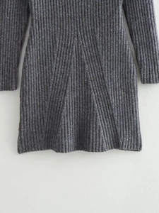 Détail de la texture d'une robe en maille gris foncé avec motifs côtelés et ourlet plissé