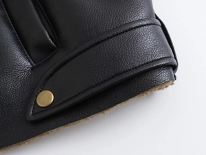 Détail d'une veste en cuir noir avec bouton en laiton et doublure chaude en polaire marron