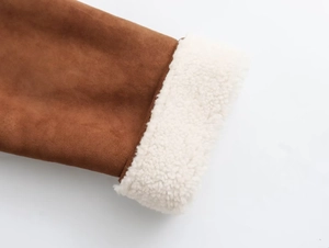 Detailed close-up of brown suede cuff featuring thick white faux shearling lining