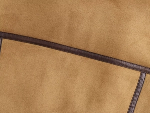 Détail du gilet en daim camel avec passepoil en cuir marron et coutures de précision