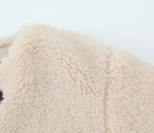Close-up of soft beige sherpa fleece texture on a warm long-sleeve winter jacket