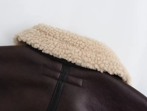 Detail einer braunen Lederjacke mit flauschigem cremefarbenem Lammfellkragen und Naht