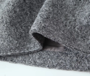 Detailed view of gray bouclé fabric texture and fine stitching on the short jacket