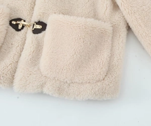 Detail of beige fleece jacket featuring toggle closures with leather patches and large pocket