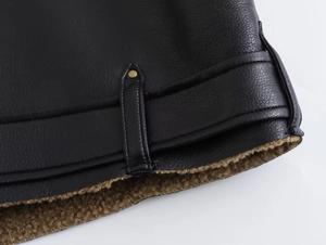Détail de veste en cuir grainé noir avec doublure en fausse fourrure et clou doré