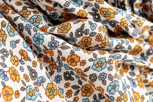 Close-up of floral fabric with blue and orange petals on a soft white background