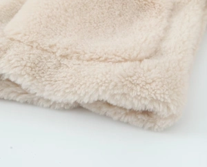 Close-up of soft cream fleece fabric texture with thick fluffy material and stitching