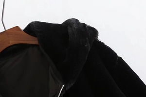 Close-up of black faux fur hooded jacket with shiny silver zipper and soft inner lining