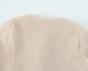 Detailed close-up of soft oatmeal fleece fabric texture on a cozy autumn jacket