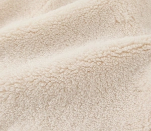 Close-up of soft cream sherpa fleece fabric texture on a long sleeve jacket