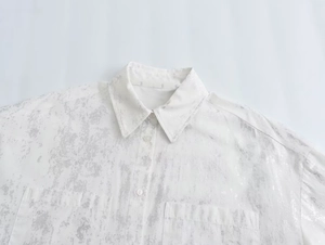 Detail of white button-down shirt featuring metallic silver print and double chest pockets