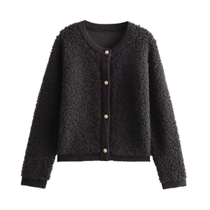 Detail of black knit cardigan featuring golden metal buttons and textured bouclé fabric