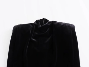 Detailed view of black velvet dress with high neck, padded shoulders and zipper back