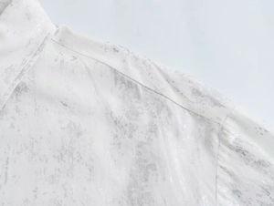 Detail of white shirt showing metallic silver foil print and high-quality fabric texture