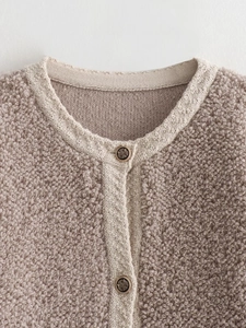Close-up of knit cardigan featuring boucle yarn texture and embossed crest metal buttons
