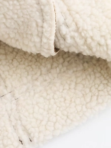 Gros plan sur la texture molletonnée crème d'un gilet sans manches vintage Y2K zippé