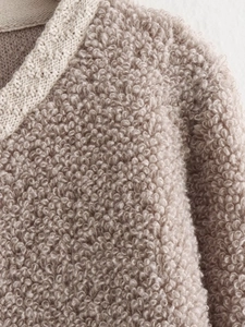 Detail view of oatmeal-colored boucle knit fabric texture with soft sherpa grain
