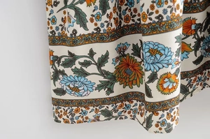 Close-up of bohemian floral print with blue and orange flowers on white dress hemline