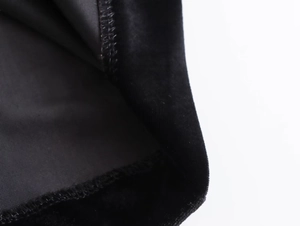 Detailed macro view of black velvet dress fabric showing premium texture and stitching