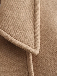 Close-up of camel wool coat showing premium twill fabric texture and precise stitching detail