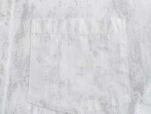 Macro shot of a white Y2K shirt featuring metallic silver marble texture and a chest pocket